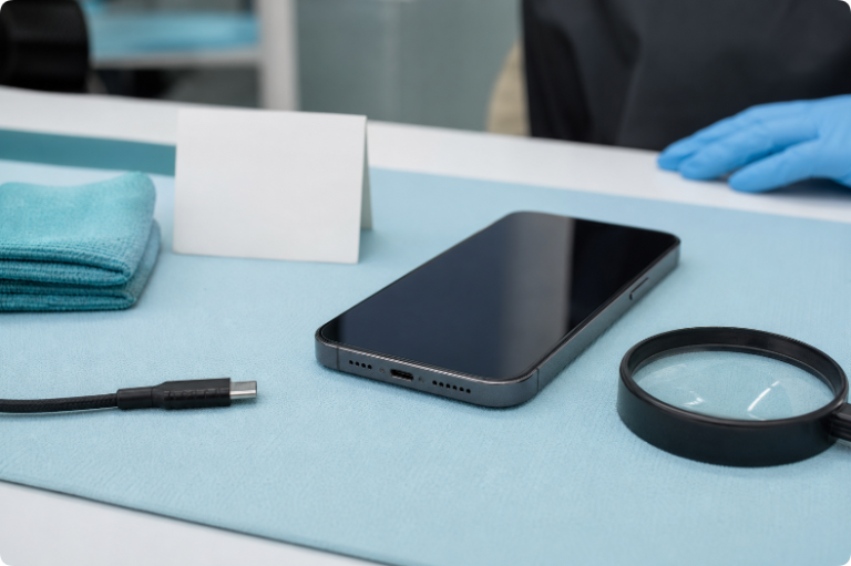 Powered-off smartphone being inspected beside a disconnected charging cable